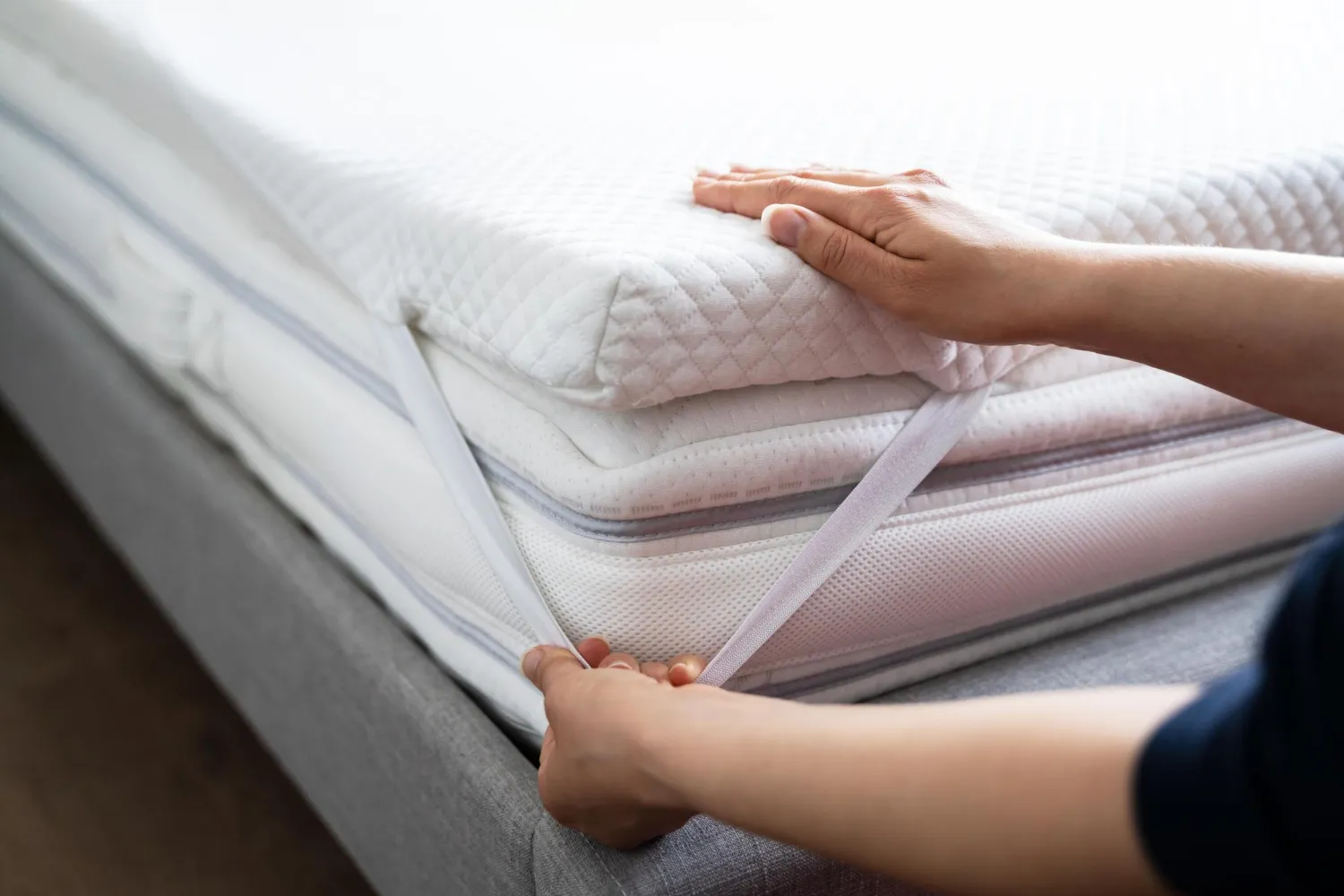 Une femme pose un surmatelas sur un lit